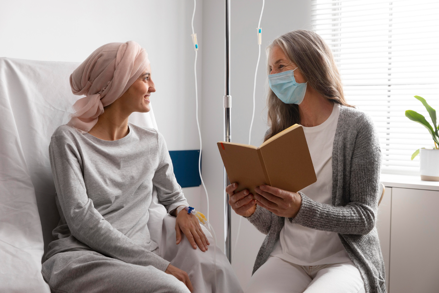 Uma mulher lendo para uma paciente com câncer que está no hospital.