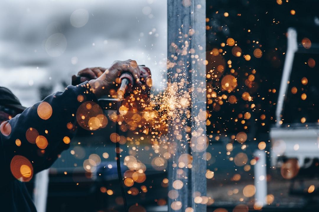 A person using a grinder to grind metal<br />
<br />
Description automatically generated