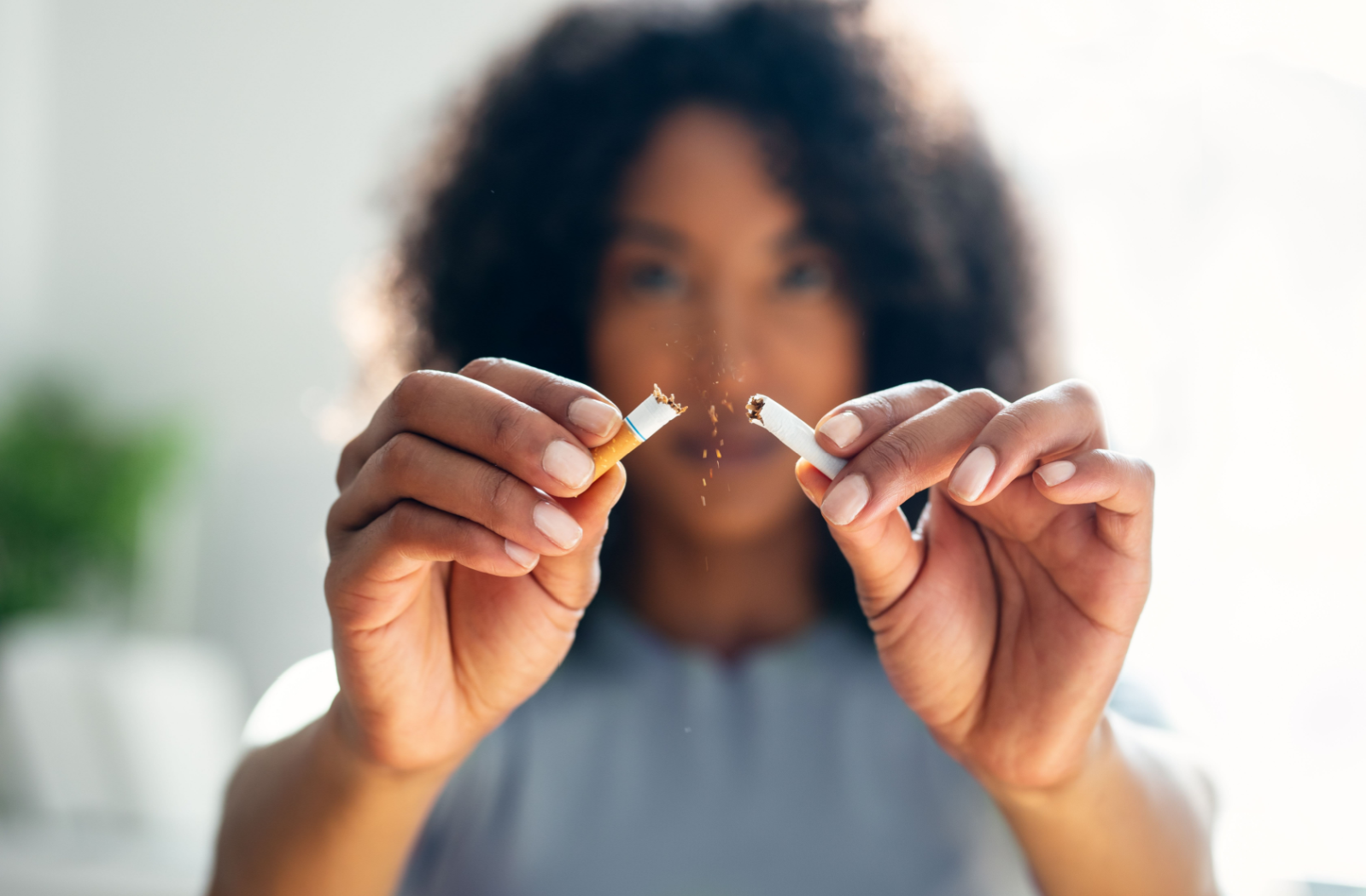 An adult holds up a cigarette and snaps it in half.