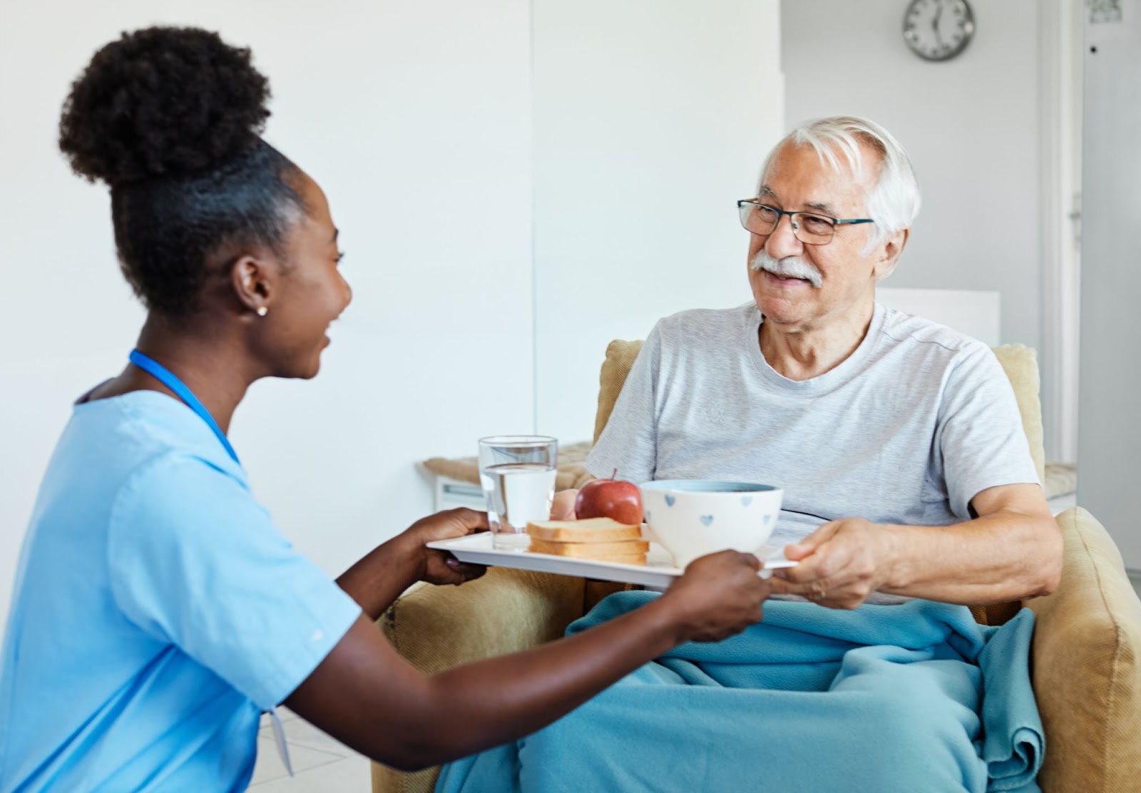 A skilled caregiver bringing a senior his meal.
