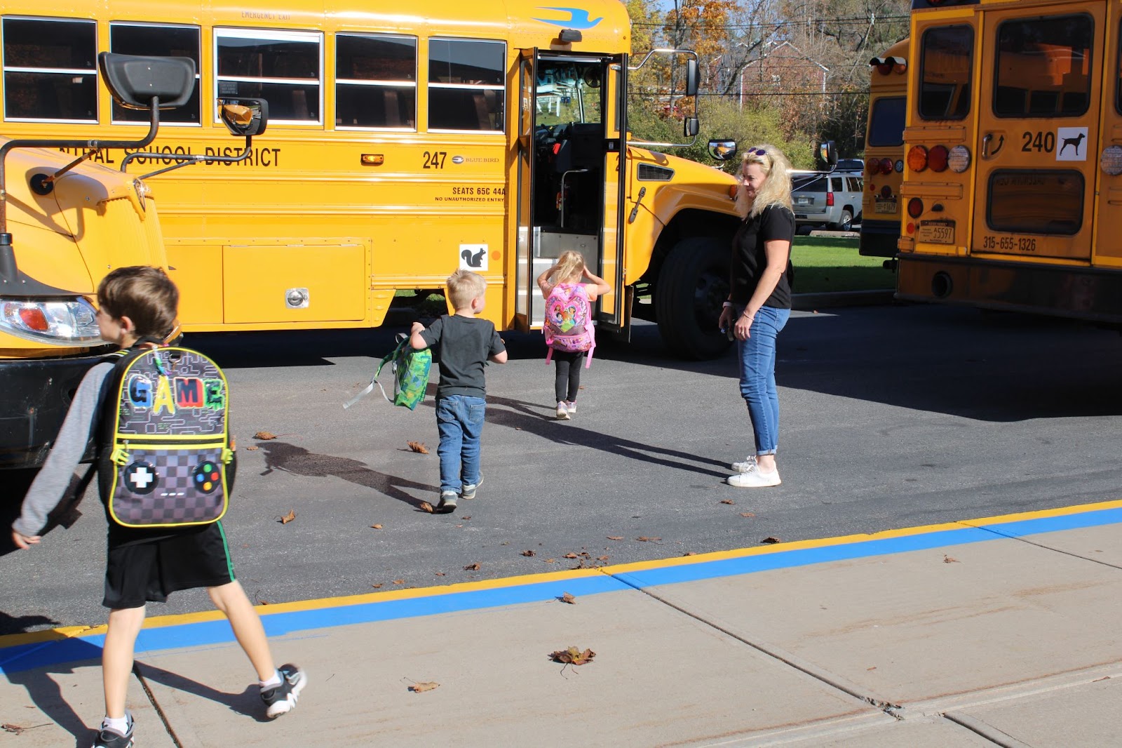 Bus driver Winnie Macheda helps young students cross the new blue safety line and get onto the bus.