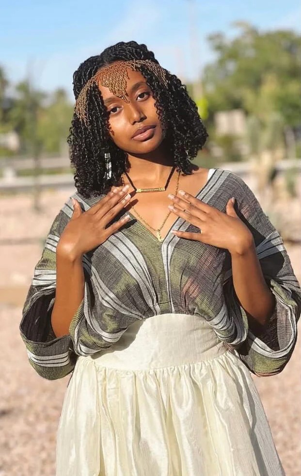 Woman wearing traditional Habesha dress with green and white stripes