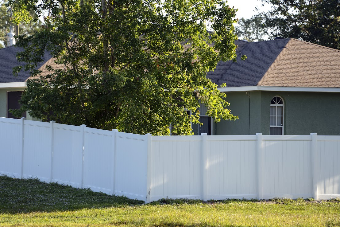 White fencing surrounds the back of a house. 