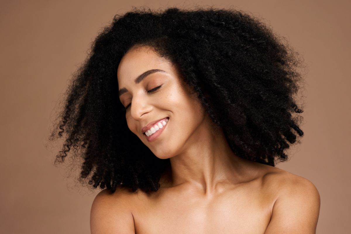 Mulher com o cabelo afro sorrindo 