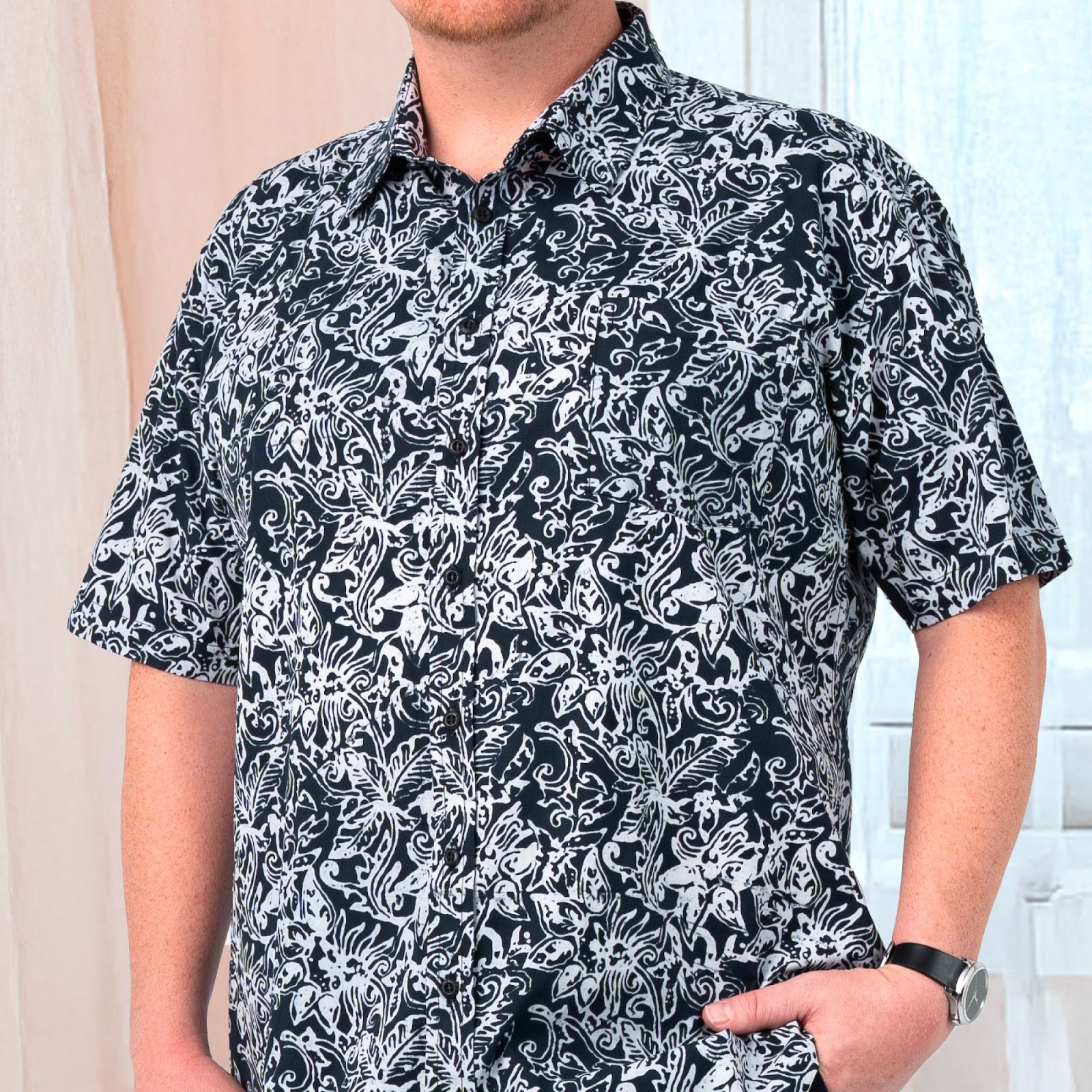A closeup image showing short sleeved men's batik shirt in black floret from batik boutique, standing in a office