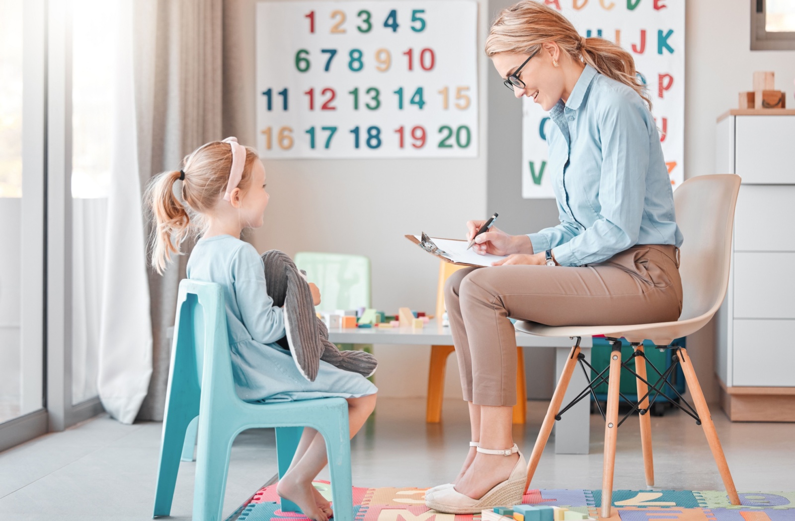 Young child sitting in a vision therapy session while an eye doctor takes notes.