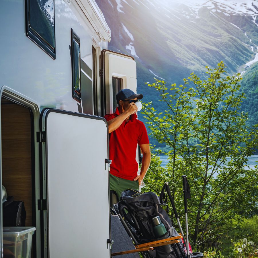 man at a scenic campsite drinking from mug