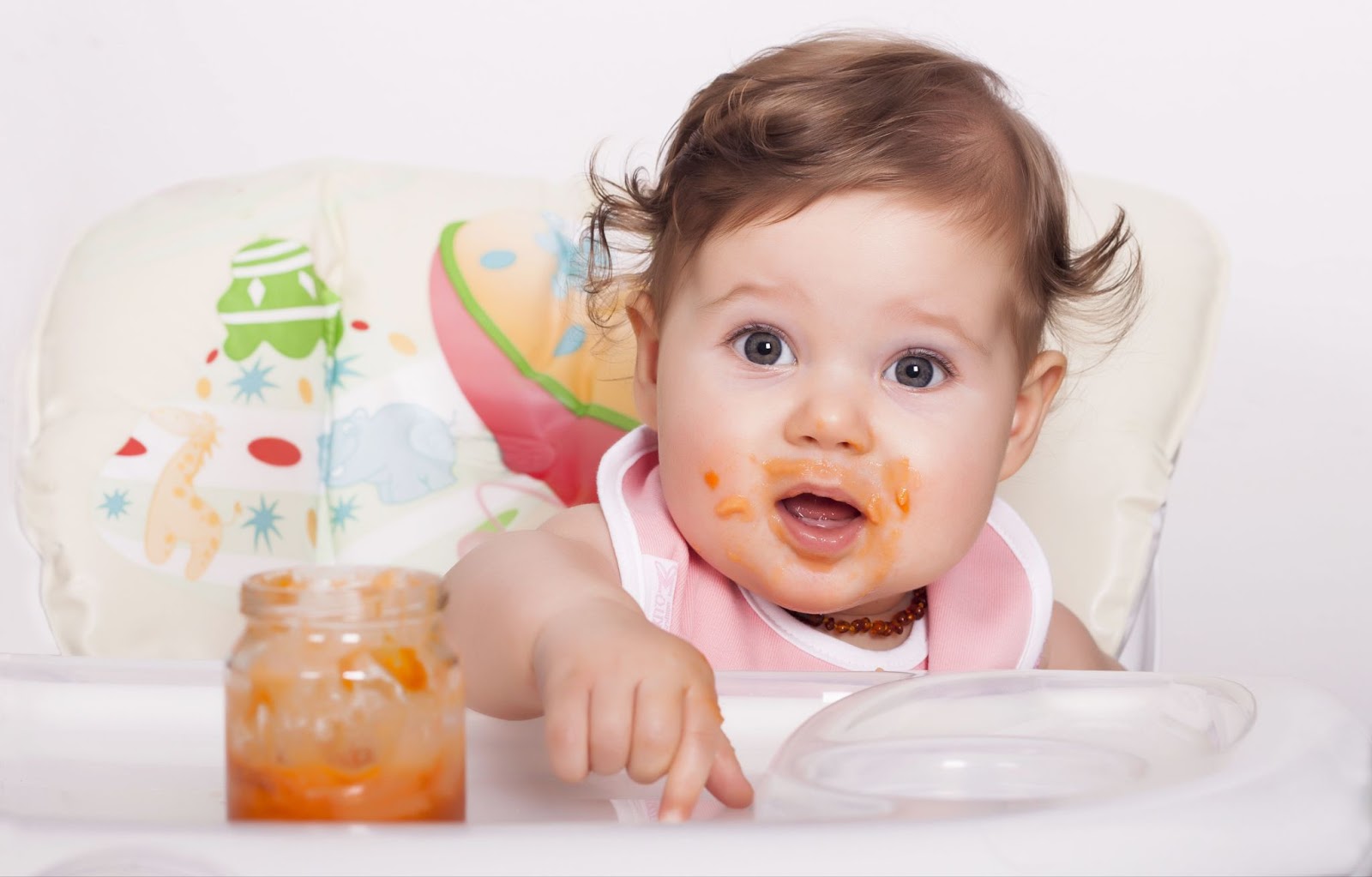 A little girl enjoying her food in her high chair