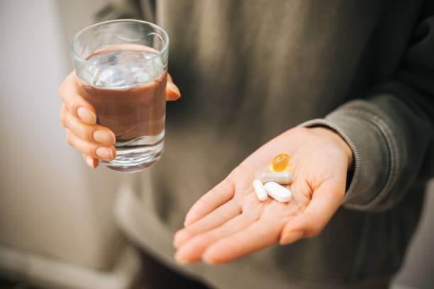 Close-up of a hand holding multivitamin pills, symbolizing a healthy supplement routine for cancer recovery.