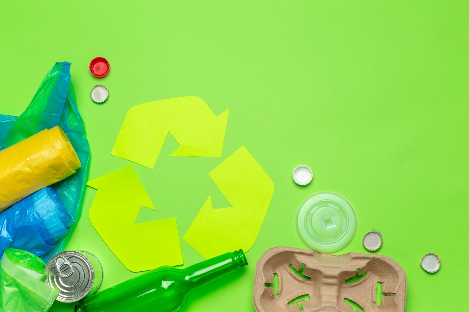 Recycling symbol next to cardboard, cans, and bottles. 