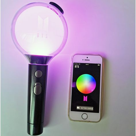 This contain an image of  ARMY bomb lightstick cell phone sitting next to a light on top of a white table with a purple light