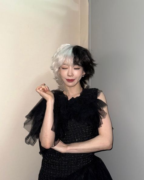 This contain a picture of TAEYEON  with white hair wearing a black dress and holding her hand on her chest