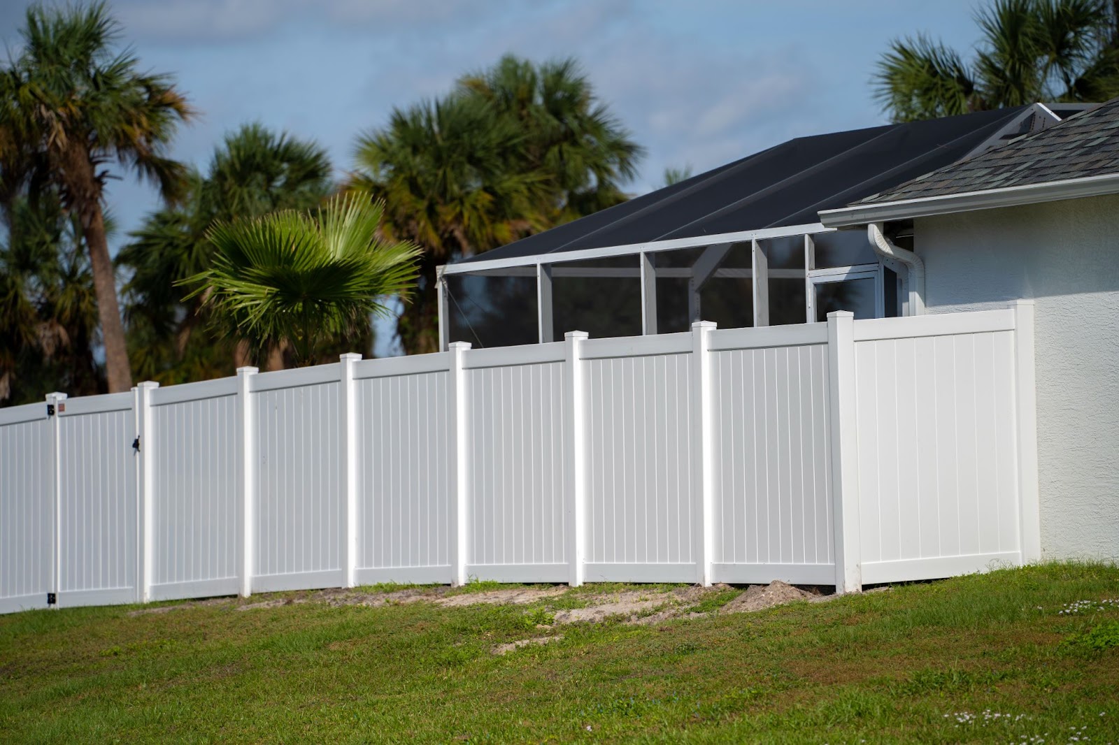 Classic white vinyl picket fence bordering a vibrant green lawn enclosing the property grounds.