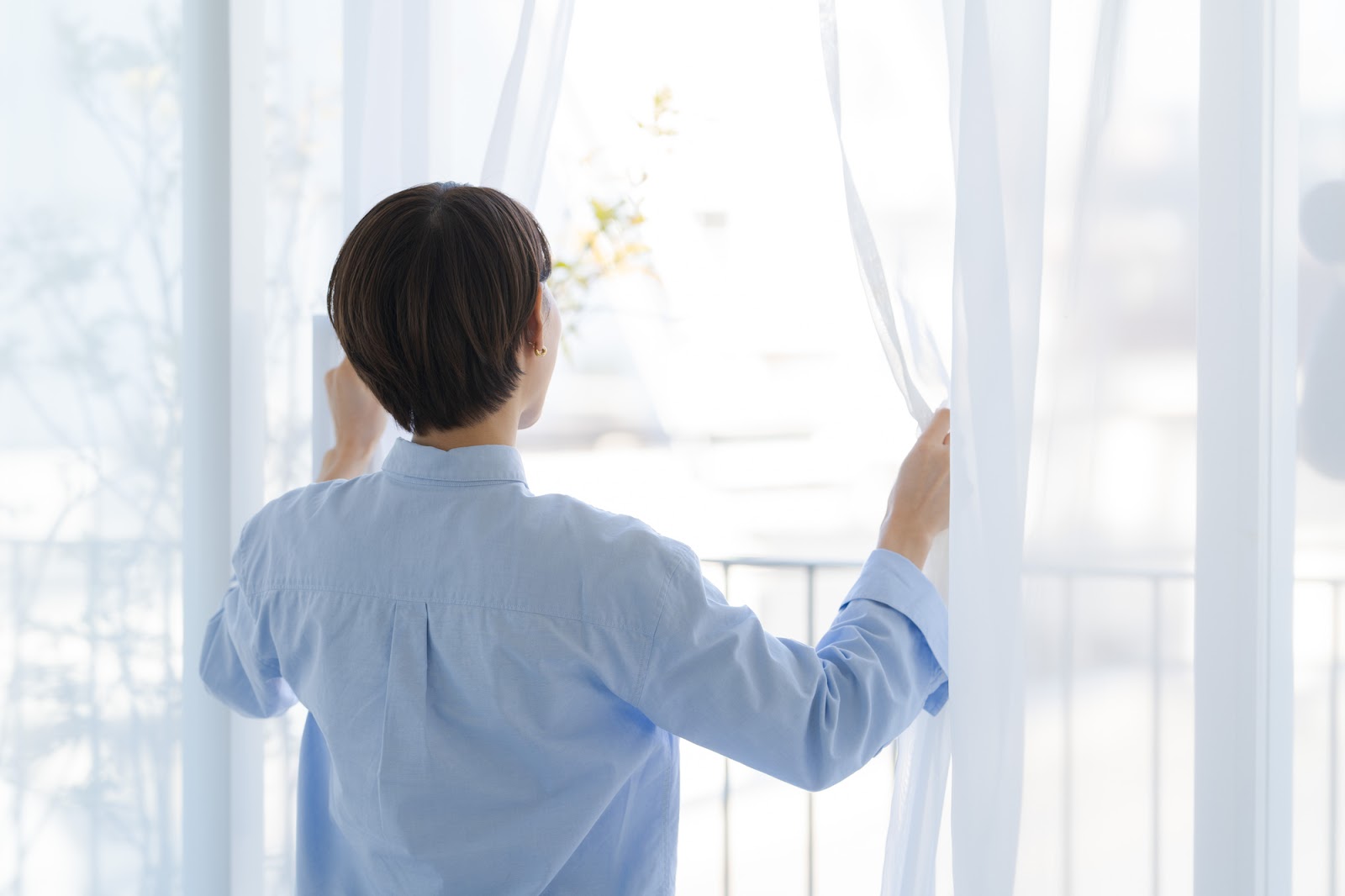 注文住宅のカーテンを開ける女性