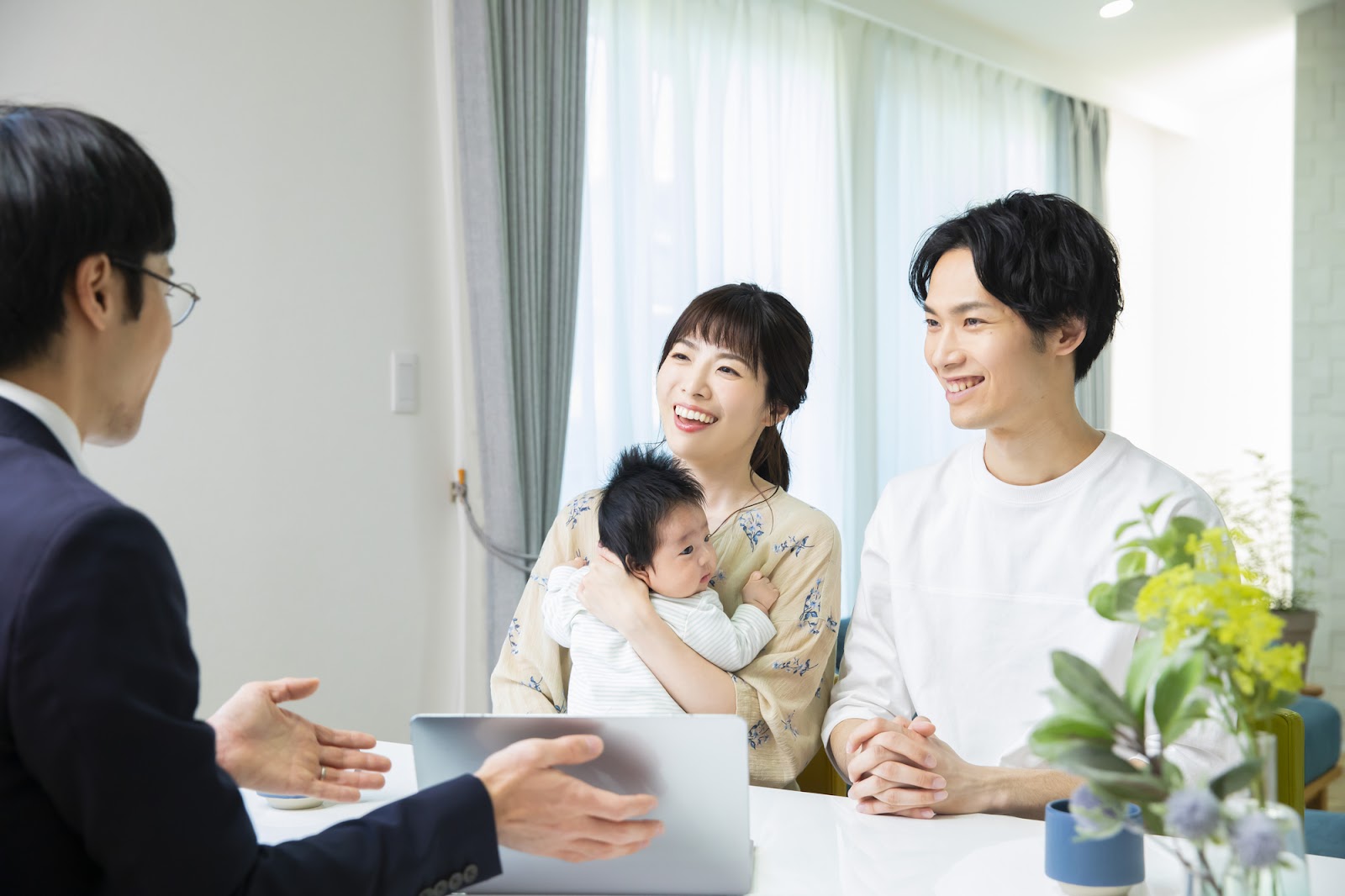 住宅ローンの相談をする若い夫婦と赤ちゃんのいる家族