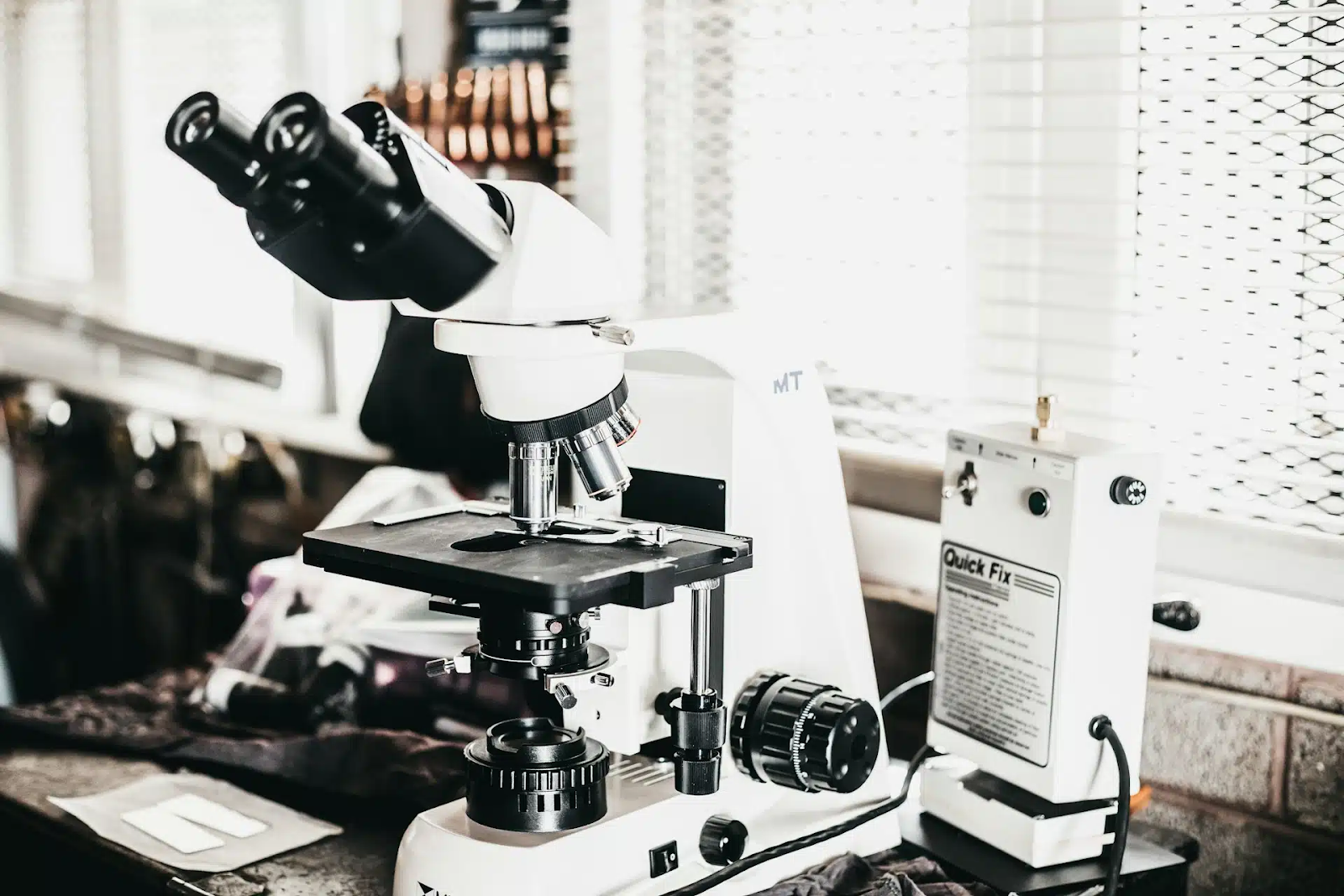 close-up-of-white-compound-microscope-on-laboratory-desk-with-adjustment-knobs-and-electronic-device-connected-exposing-the-real-cartalax-benefits-cellular-regeneration-beyond-the-systems-control-tony-huge