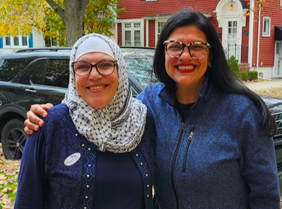 Rashida smiles with a woman wearing a hijab.