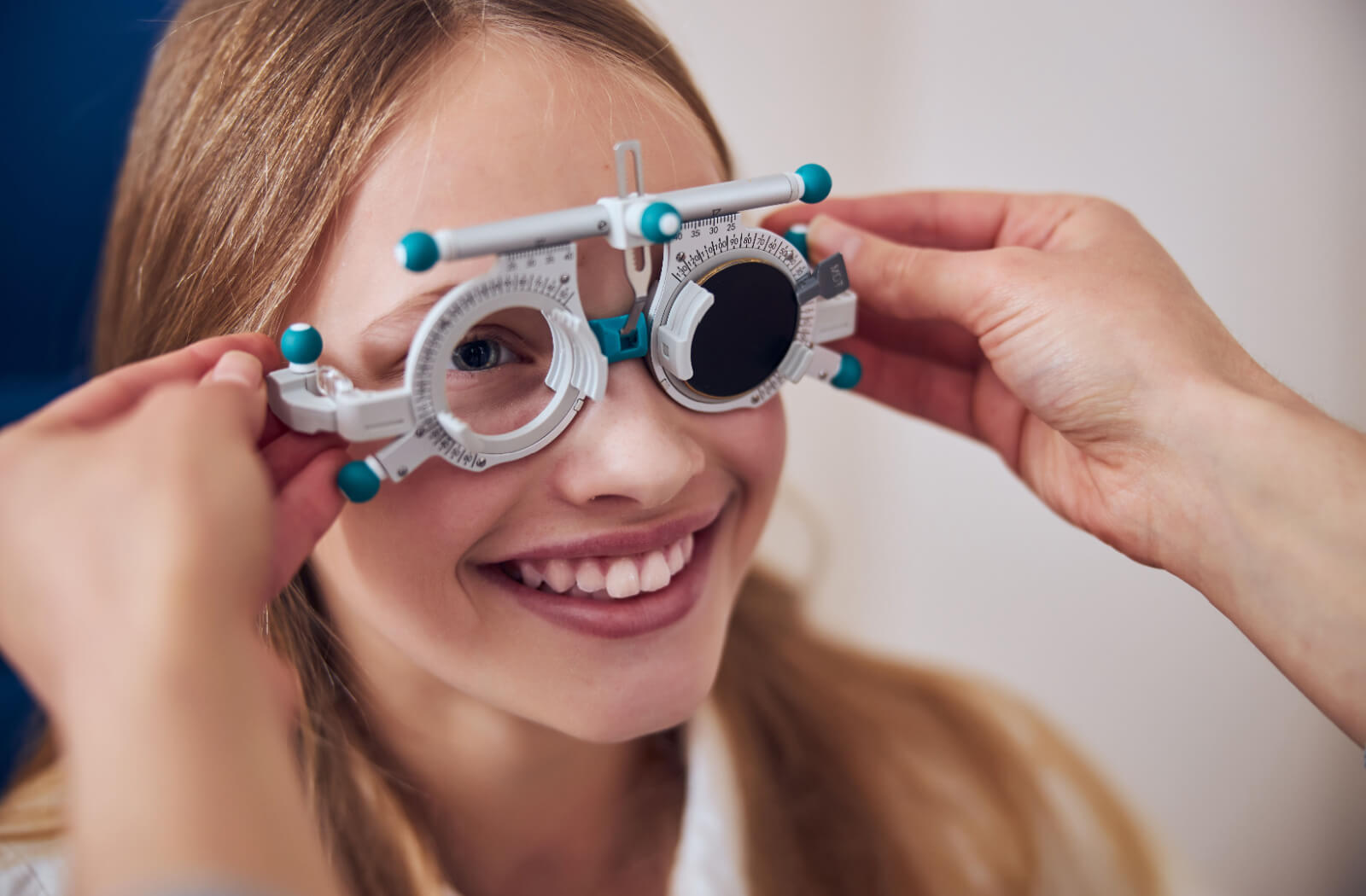 A close-up image of a smiling young adult during an eye exam to create their vision therapy treatment plan.