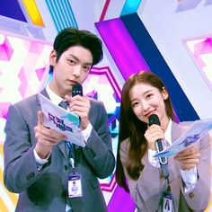 This contains an image of Wonyoung and Sunghoon standing next to each other with microphones in their hands and one person holding something