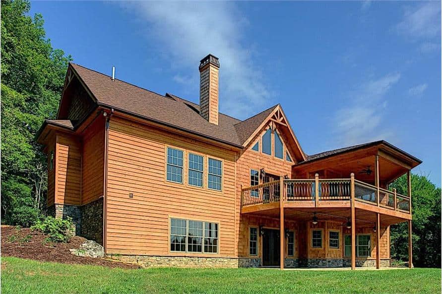 Rear exterior view showing its wood siding, a sunny deck, and covered porches.