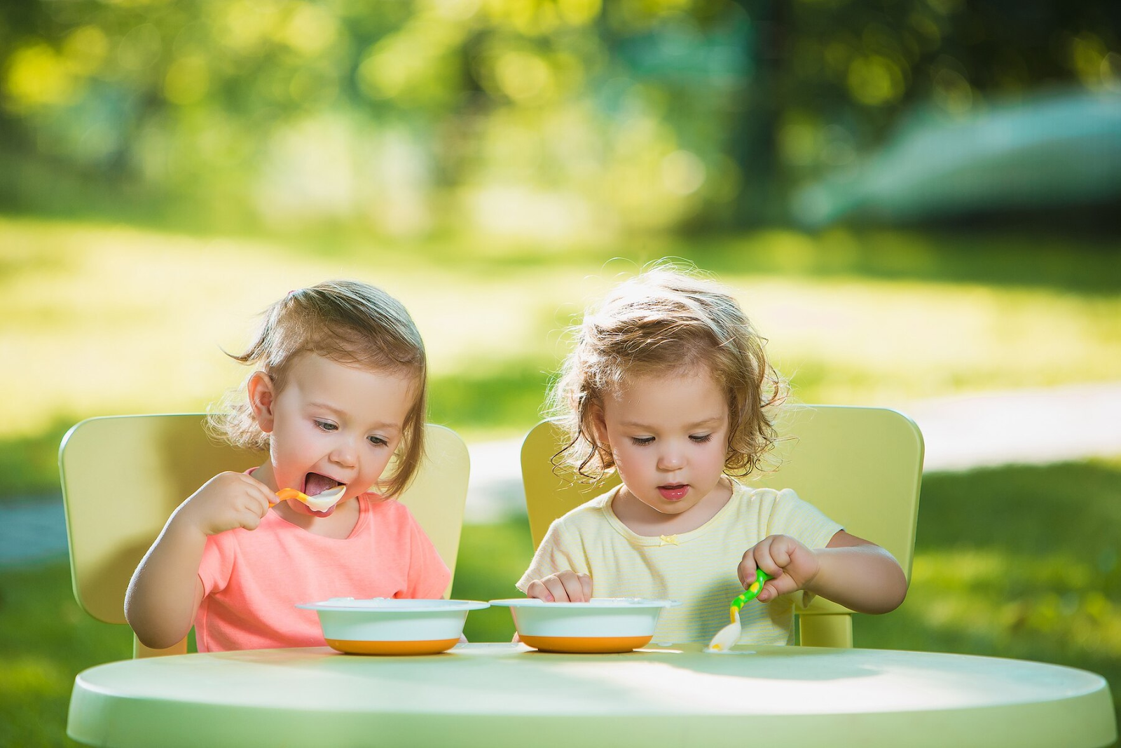 Two little girls sitting at a table and eating together