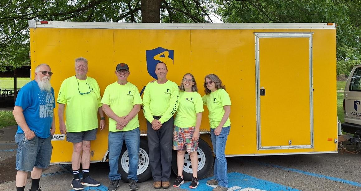 A group of people standing in front of a yellow trailer

AI-generated content may be incorrect.