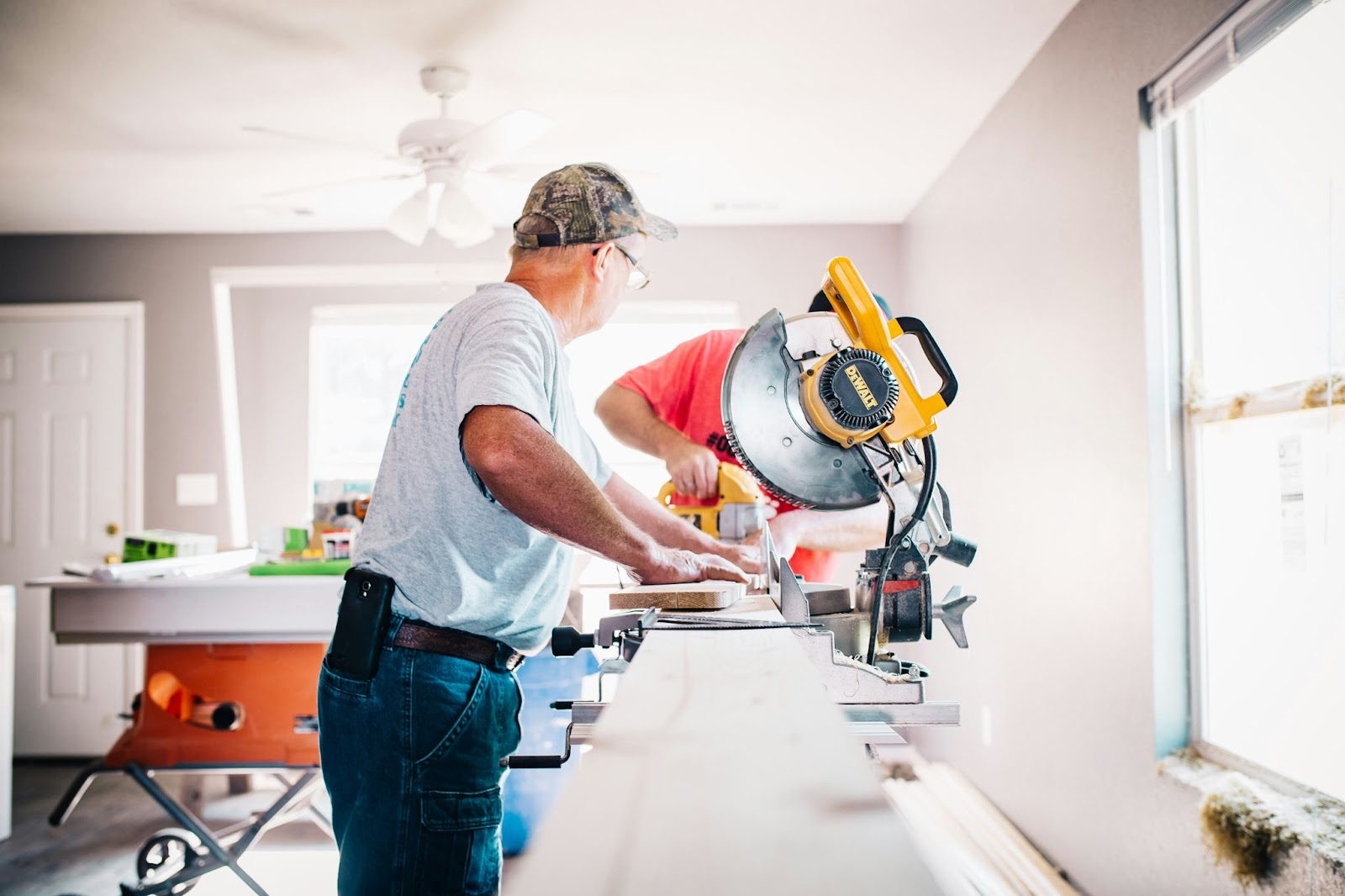 This image depicts a person operating a miter saw in a woodworking workshop.