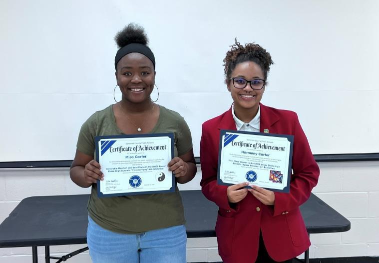 Two smiling young women holding certificates