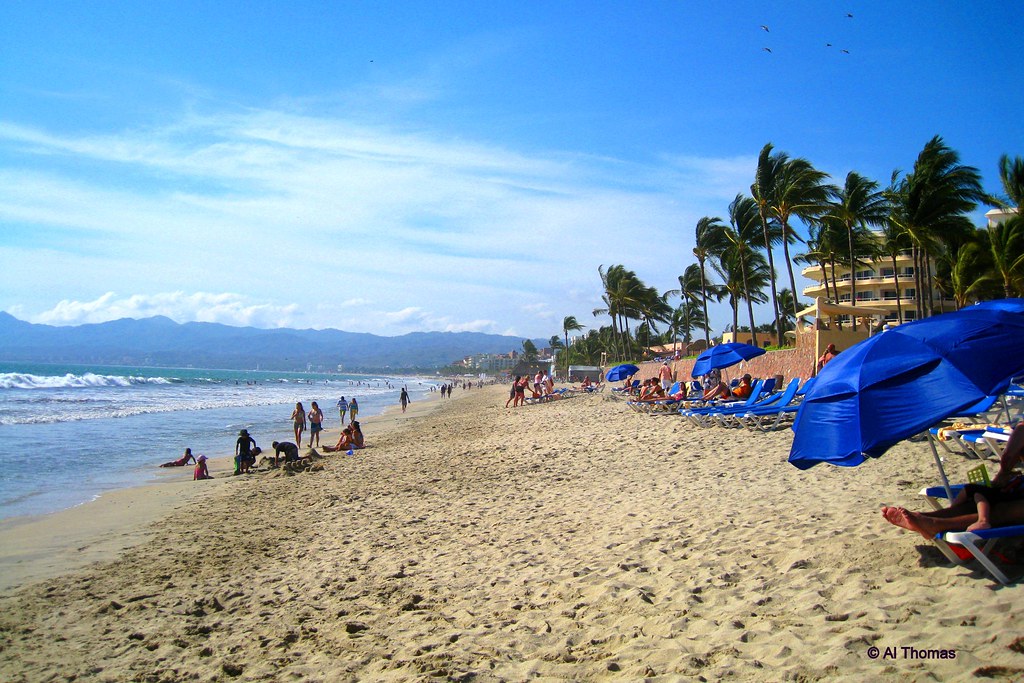 People are enjoying on the beach in puerto vallarta some are sitting on the chair while some are enjoying on the sand