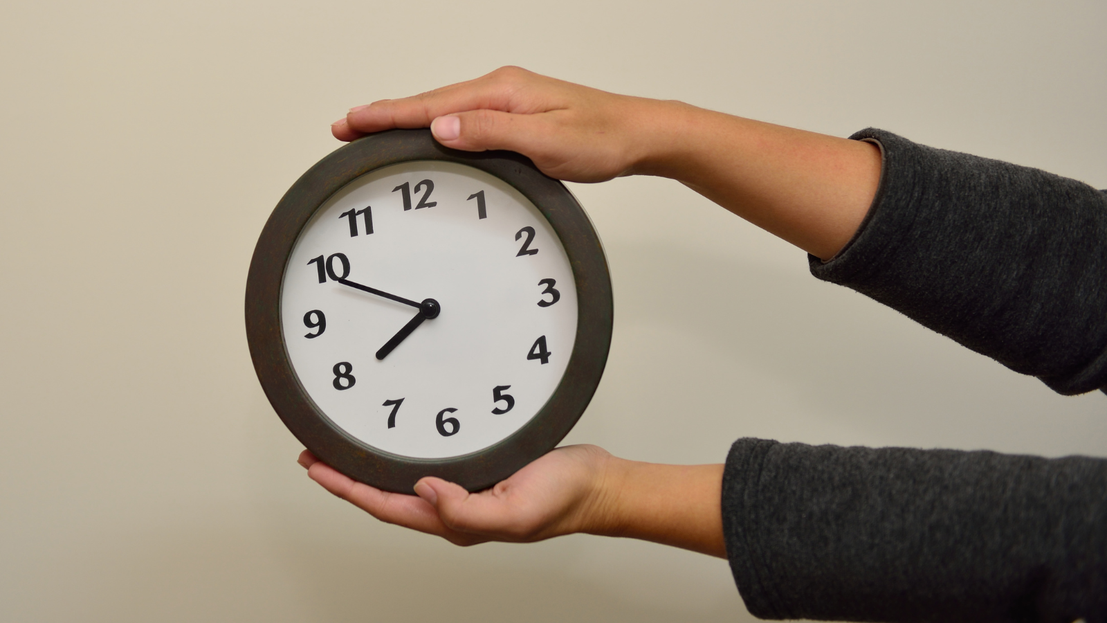 A person holding a round wall clock with both hands, symbolizing the importance of timing. This image visually supports the blog topic "Optimize Your Cart with A/B Testing Using Supercart: Why You Should Start Today" by representing the concept of perfect timing and data-driven decision-making in eCommerce.