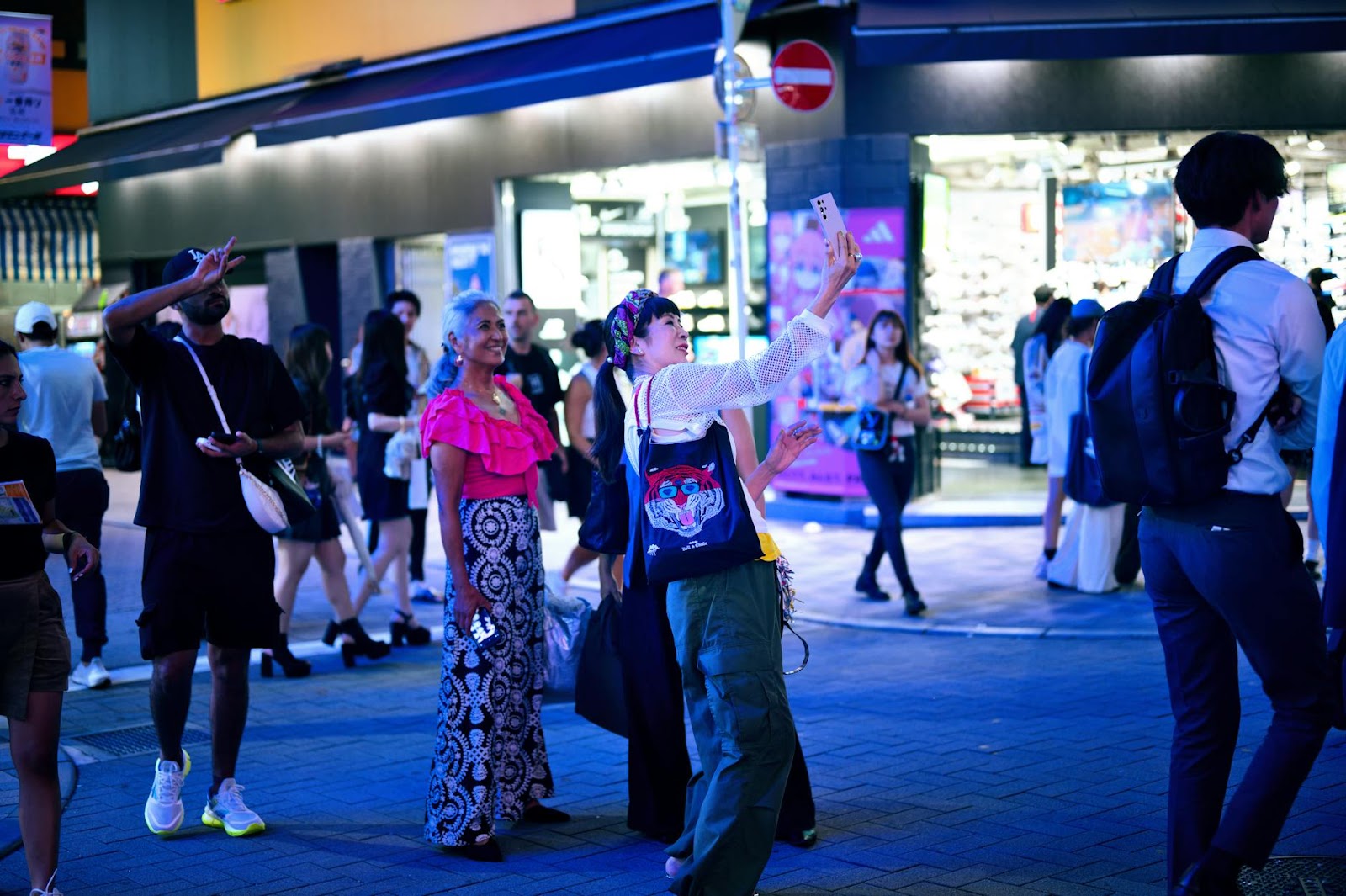 People enjoying a lively night scene in Tokyo, capturing moments and exploring the city.
