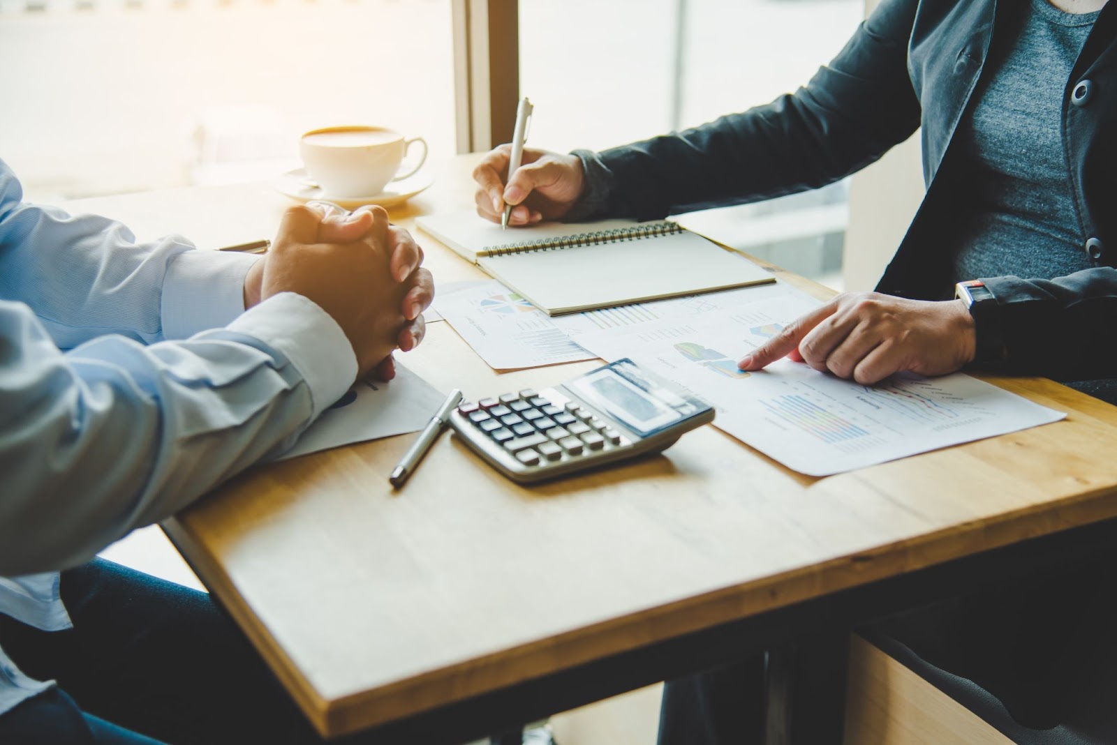 Close-up of two business professionals at a desk, one explaining details to the other during a client consultation.