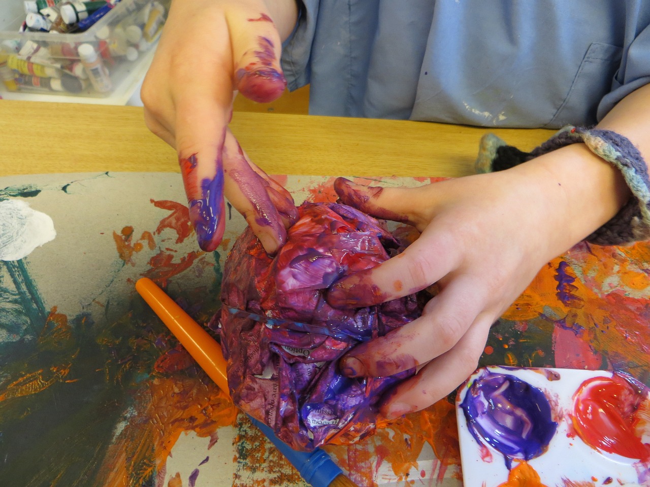 A close up of hands painting a craft.