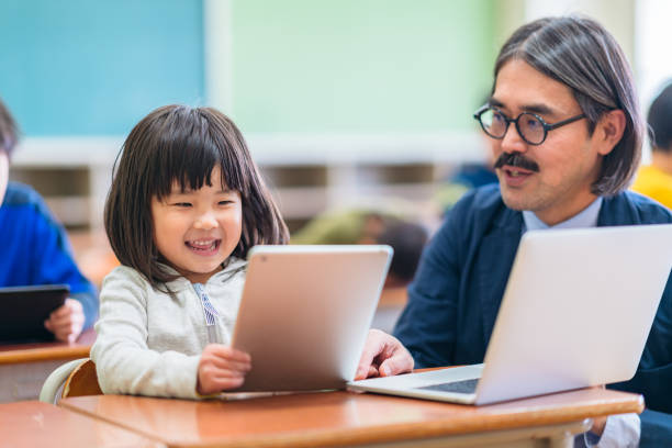 Male teacher teaching technology in elementary school in classroom A male teacher teaching is technology in elementary school in classroom. japan ed-tech stock pictures, royalty-free photos & images