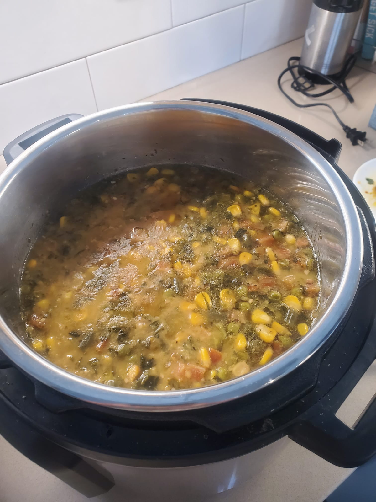 A soup full of vegetables bubbles in a pot.