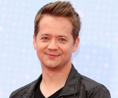 This contain Jason Earles wearing a black shirt and jacket smiling 