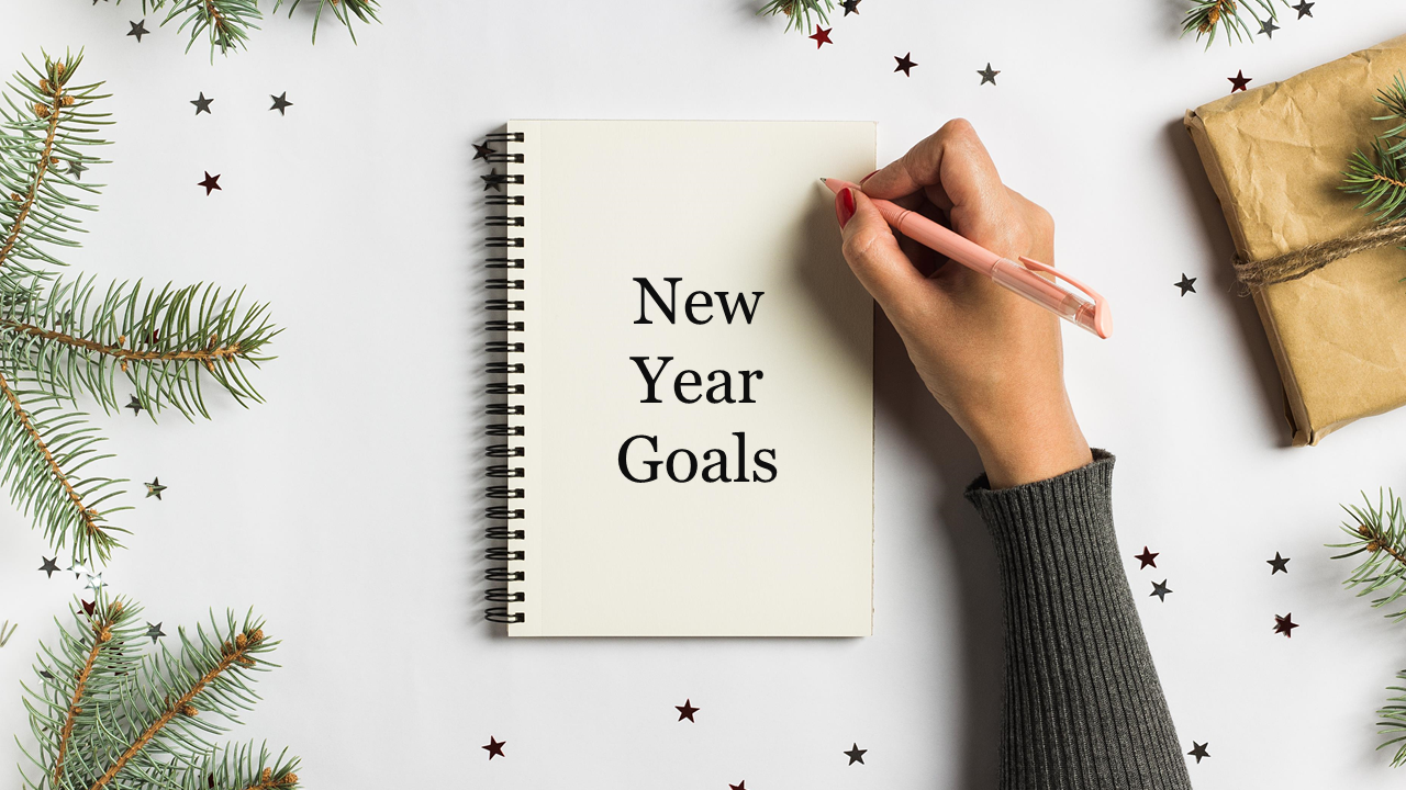 Notebook titled 'New Year Goals' with a hand holding a pen, surrounded by festive pine branches and star confetti.