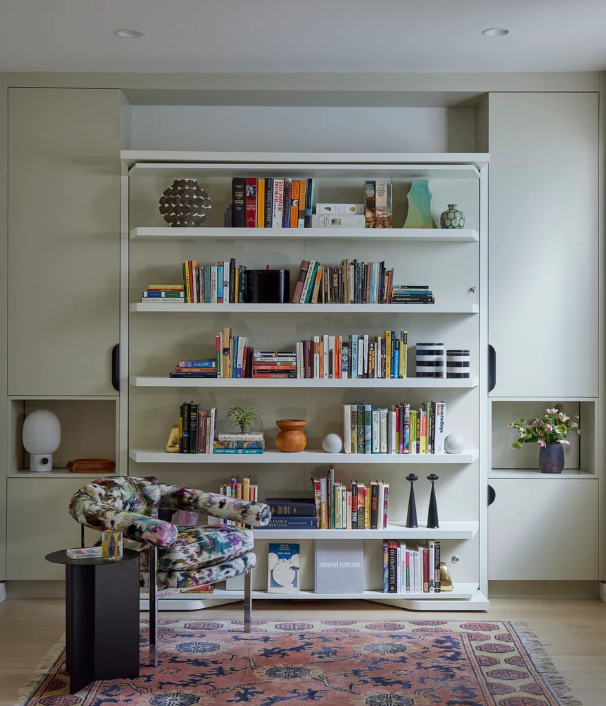 Contemporary reading nook featuring a white wall bed with built-in shelving, integrated cabinetry, and a multicolor modern armchair.
