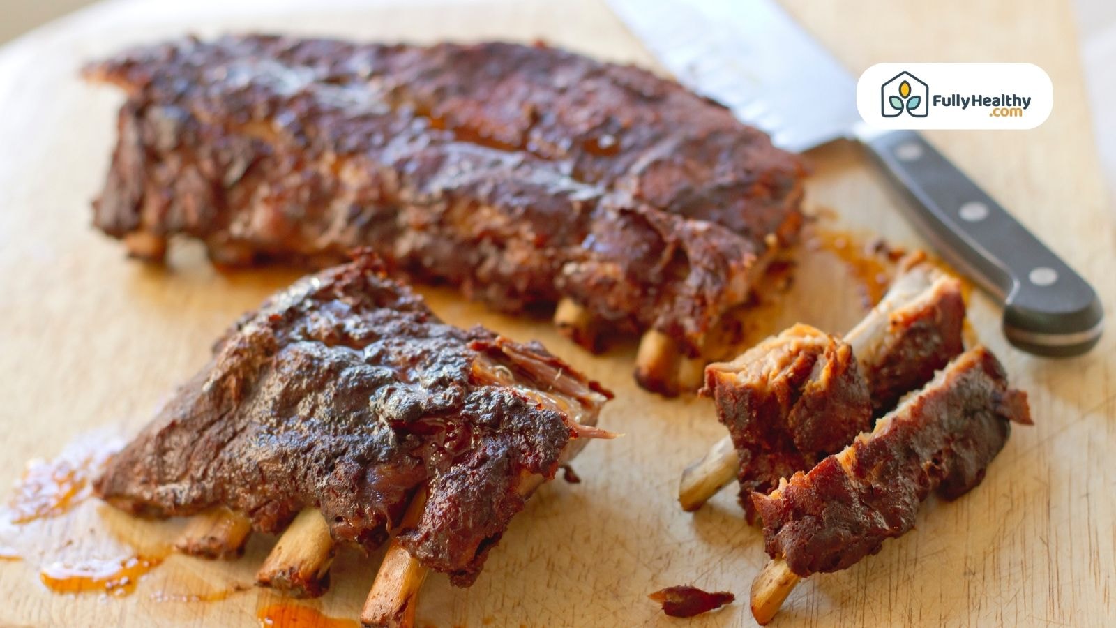 Cooked barbecue baby back ribs sliced on cutting board with knife