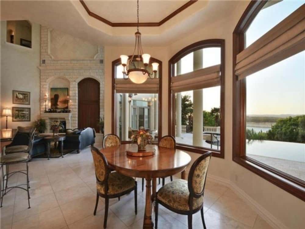 The breakfast nook offers a round dining set, a warm chandelier, and a bay window overlooking an expansive view.