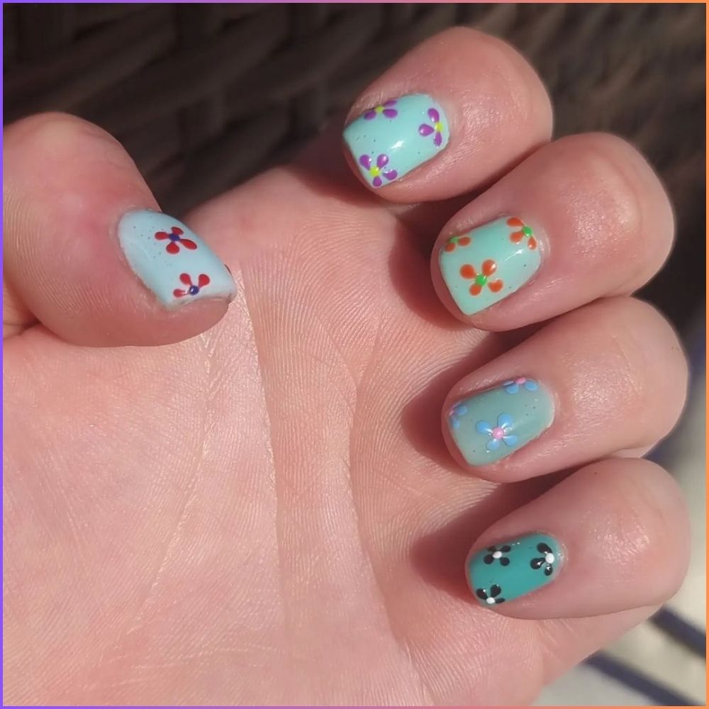 Close up of hands with flowered designed blue nails having Mix Up with Different Colors