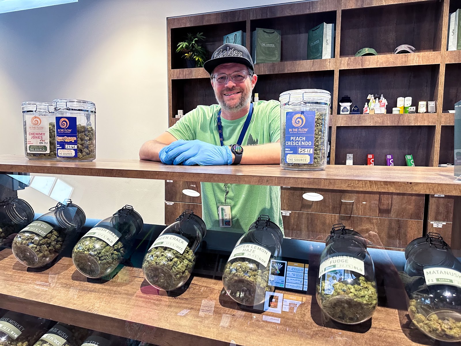  Budtender, Shaun Forrester, smiles behind the deli-style cannabis flower display at The Source cannabis dispensary in Rogers, Arkansas.