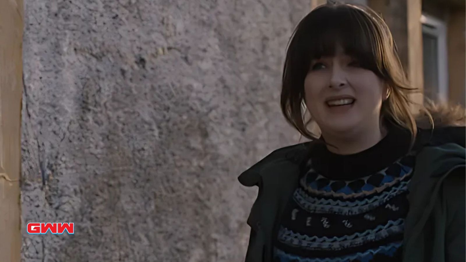 Tosh McIntosh smiling outside a stone wall in Shetland village