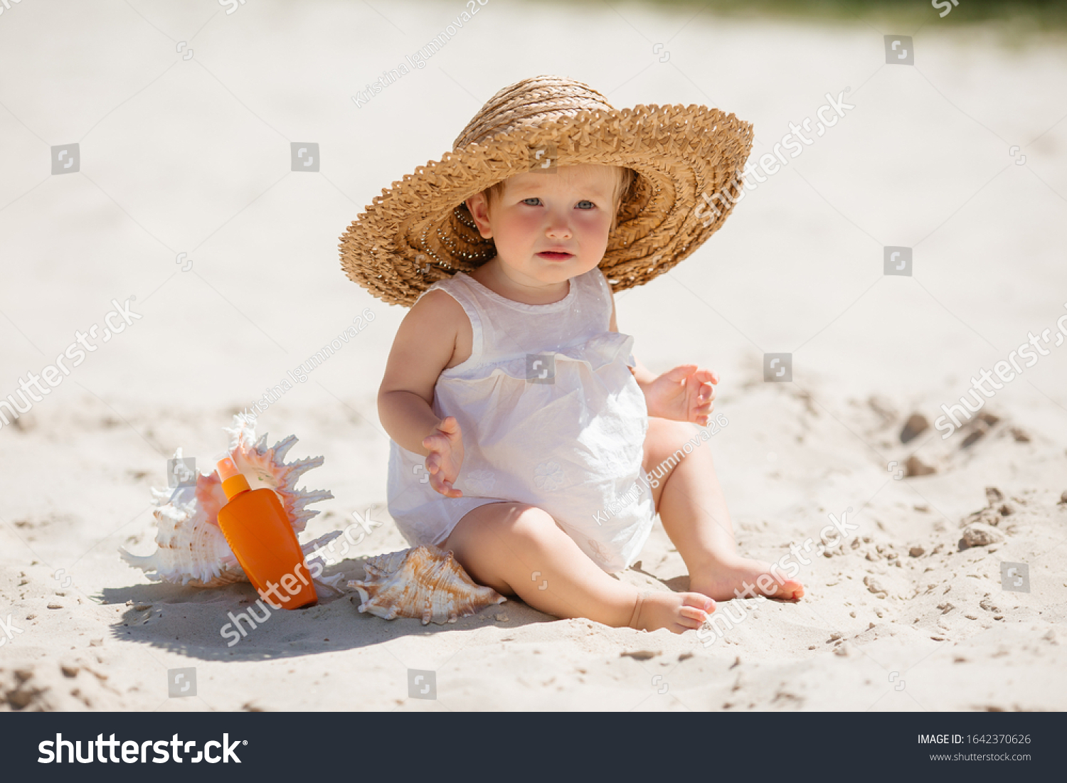 Bebé con sombrero grande en la playa, protegido del sol para cuidar su salud ocular.
