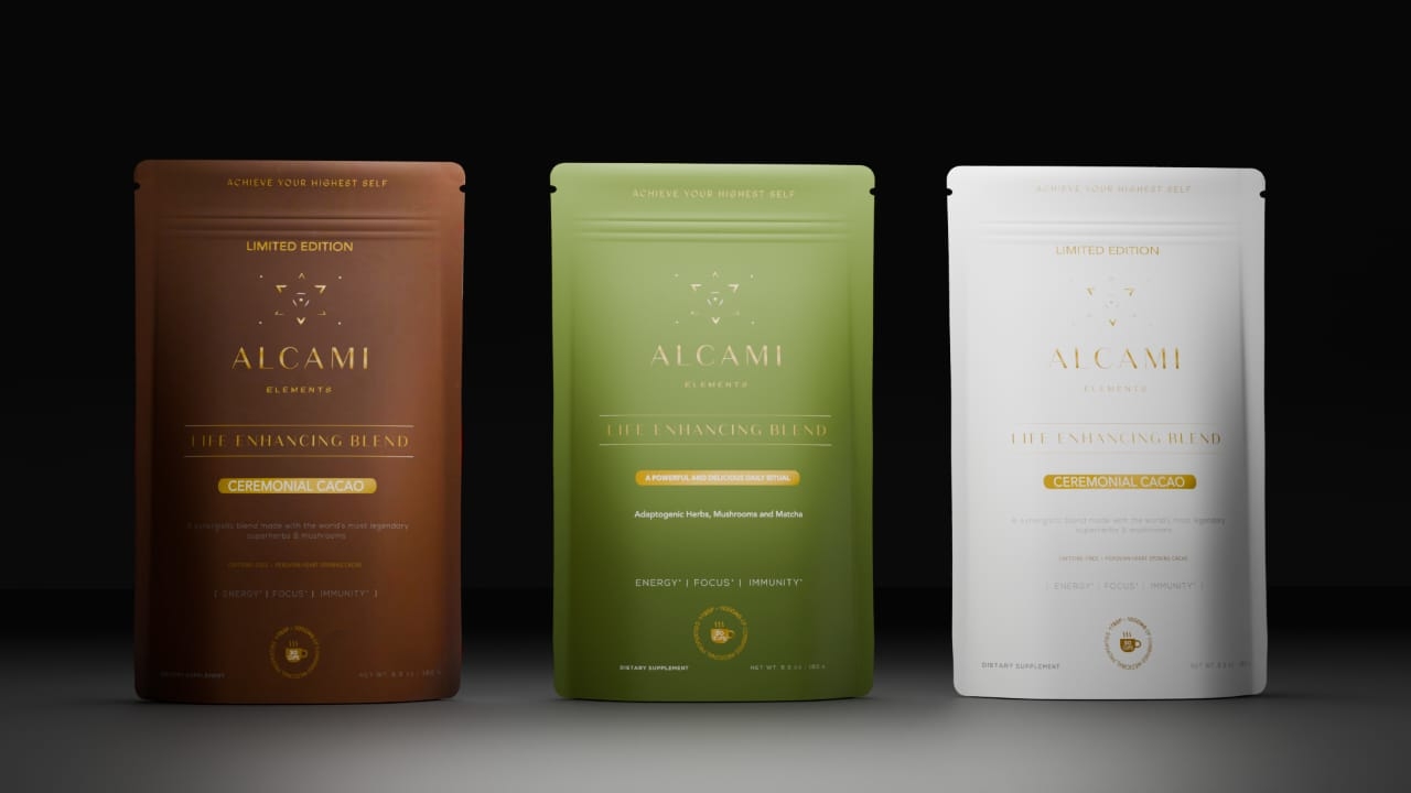 Three Alcami Elite Enhancing Blend pouches in brown, green, and white, standing against a dark background. Each pouch features gold lettering and a minimalist design.