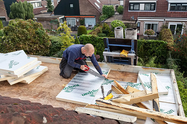 A man carefully cuts insulation with a saw while constructing a house.