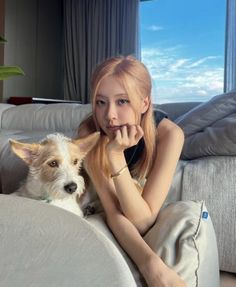 This contains an image of BLACKPINK Rosé sitting on a couch next to a dog with her hand on her chin