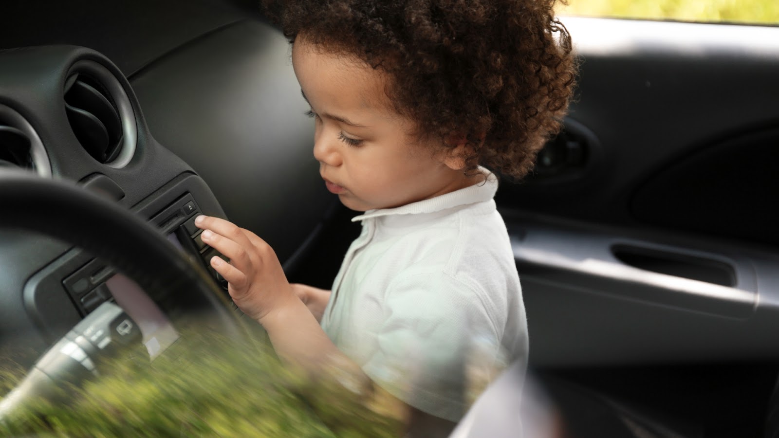 Young child alone in a vehicle, highlighting the dangers of vehicle lockouts during summer trips.