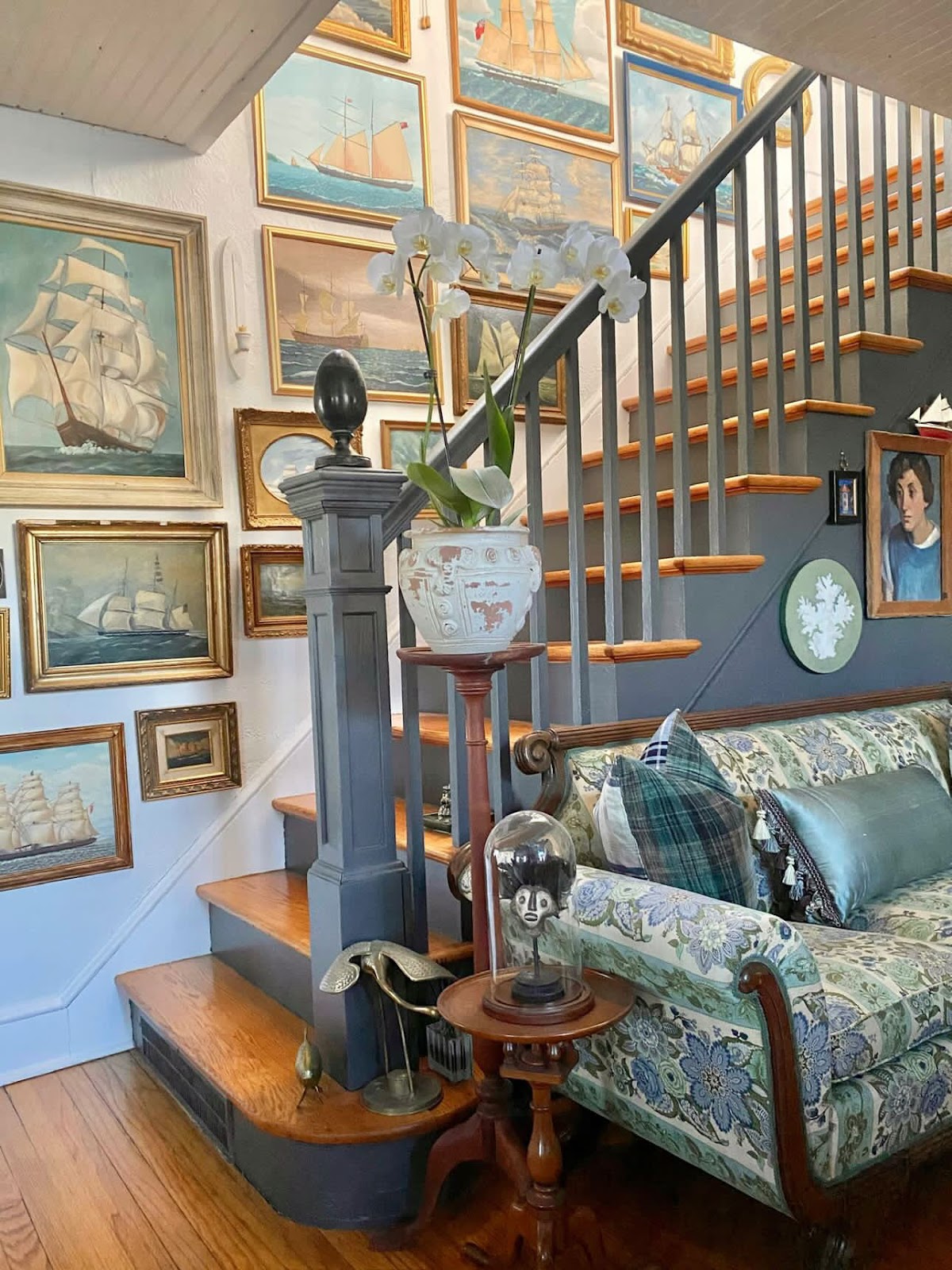 A gallery wall full of ship paintings hung asymmetrically alongside the stairway. 