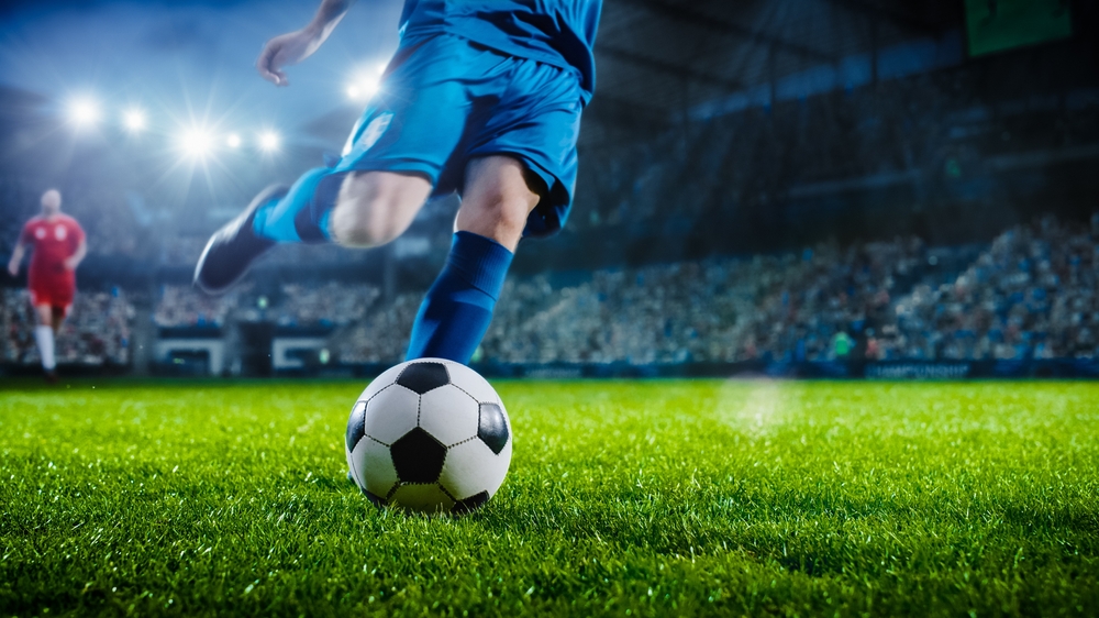 A soccer player kicking a ball, displaying peak performance.